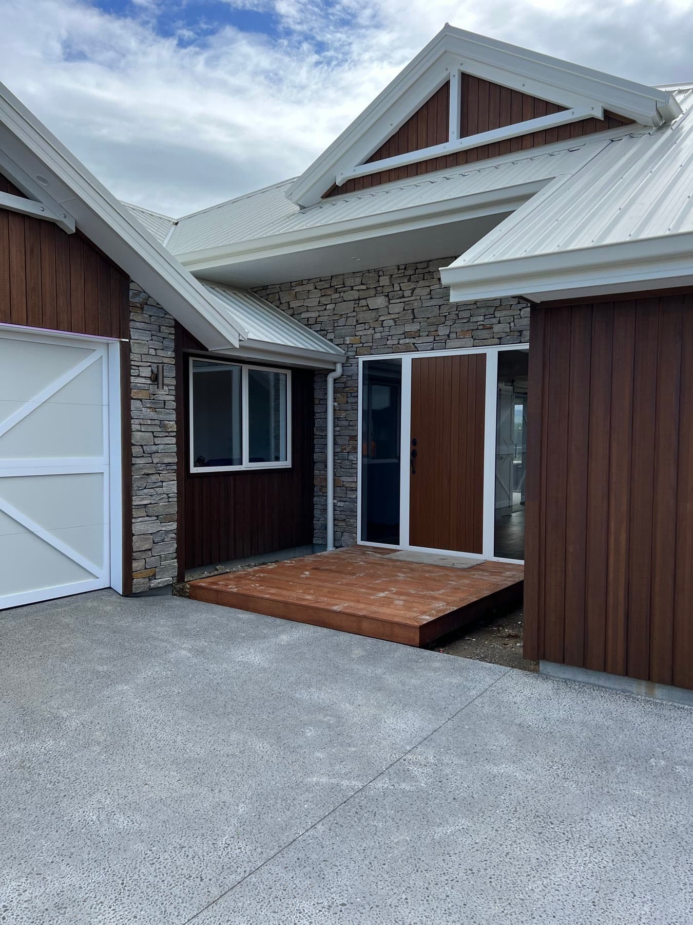 The finished front entry: stacked stone, vertical cedar cladding and a timber step